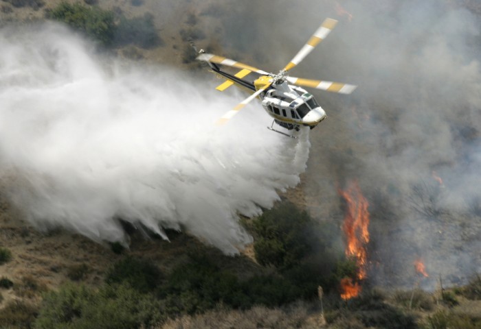 Image of a helicopter spraying water over a bushfire